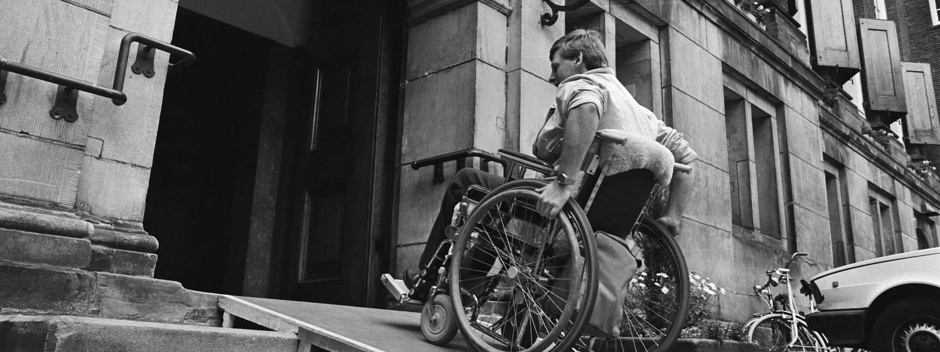 Man in rolstoel gebruikt aangepaste ingang