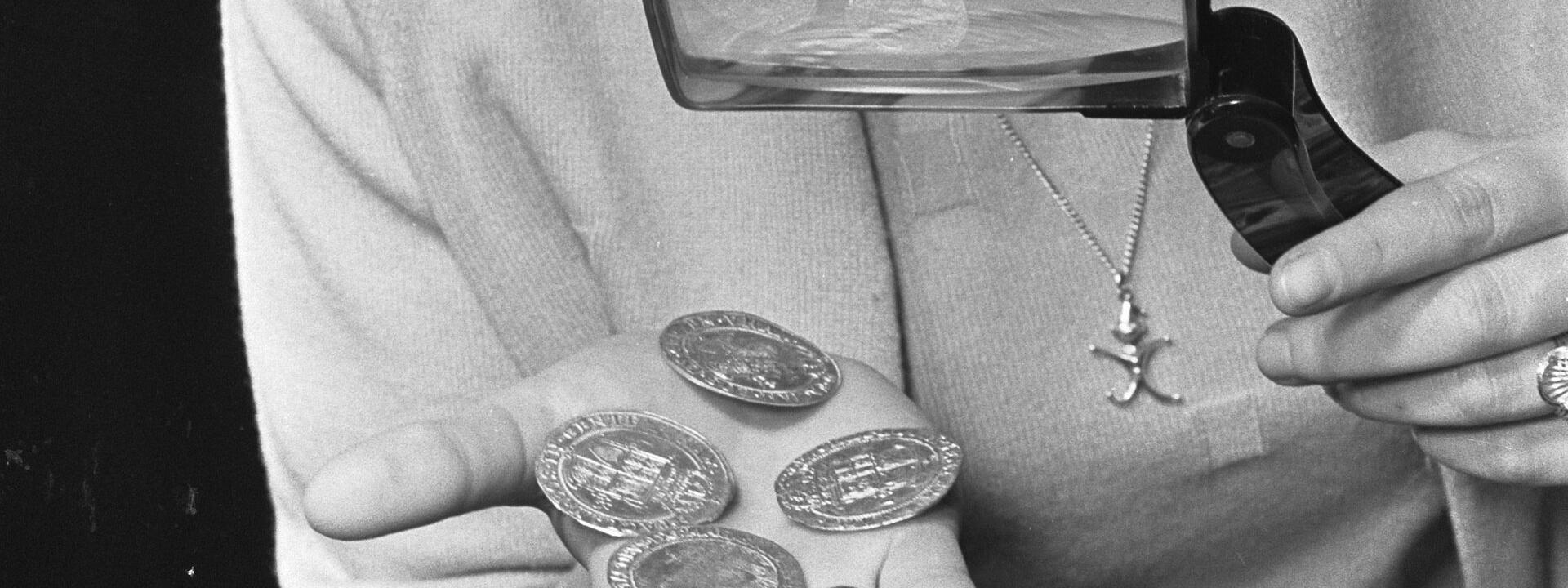 Woman looking at coins through looking glass